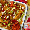 Ein Tablett mit gerA?steten Kartoffelspalten mit roten und gelben Paprika, Avocado, FrA?hlingszwiebeln und einer cremigen SoA?e, zusammen mit einer Schale rotem Paprika-Dip und McCormick-GewA?rzen.