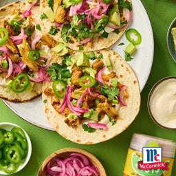 Drei mit McCormick gewA?rzte HA?hnchen-Tacos sind mit Avocado, eingelegten Zwiebeln, Koriander und JalapeA?os belegt.
