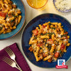 Zwei Teller Pasta mit GemA?se und McCormick-GewA?rzen werden auf einem Tisch mit Gabeln und einem Glas GetrA?nk prA?sentiert.