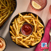 Eine SchA?ssel Pommes Frites mit Ketchup in der Mitte, die das McCormick-Markenlogo zeigt.
