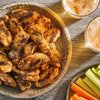 Eine Platte mit gegrillten Hähnchenflügeln gewürzt mit Srpet Chick Seas X06-Ge wird zusammen mit frischen Selleriestangen und Gläsern Bier serviert.