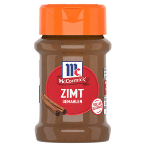 Ein durchsichtiges Plastikglas mit McCormick Zimt Gemahlen, mit einem orangefarbenen Deckel und einem roten Etikett, auf dem Zimtstangen abgebildet sind.