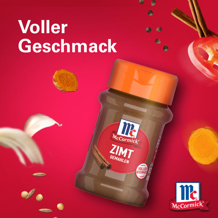 Eine Flasche Srpet Cinnamon Gd X06-Ge von McCormick wird vor einem leuchtend roten Hintergrund präsentiert umgeben von schwebenden Zutaten wie Zimtstangen und Knoblauch