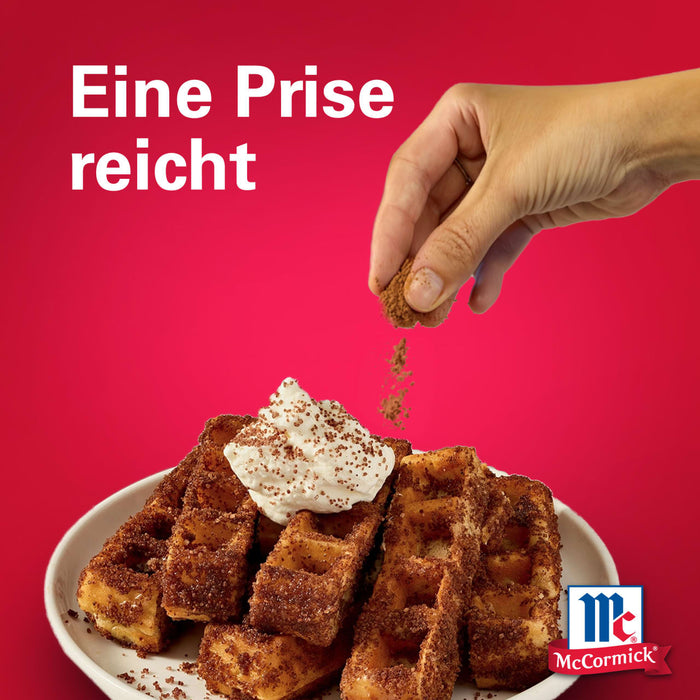 Eine Hand streut eine Prise Srpet Cinnamon Gd X06-Ge über einen Teller mit goldbraunen Waffeln und Schlagsahne vor einem roten Hintergrund mit dem McCormick Logo.