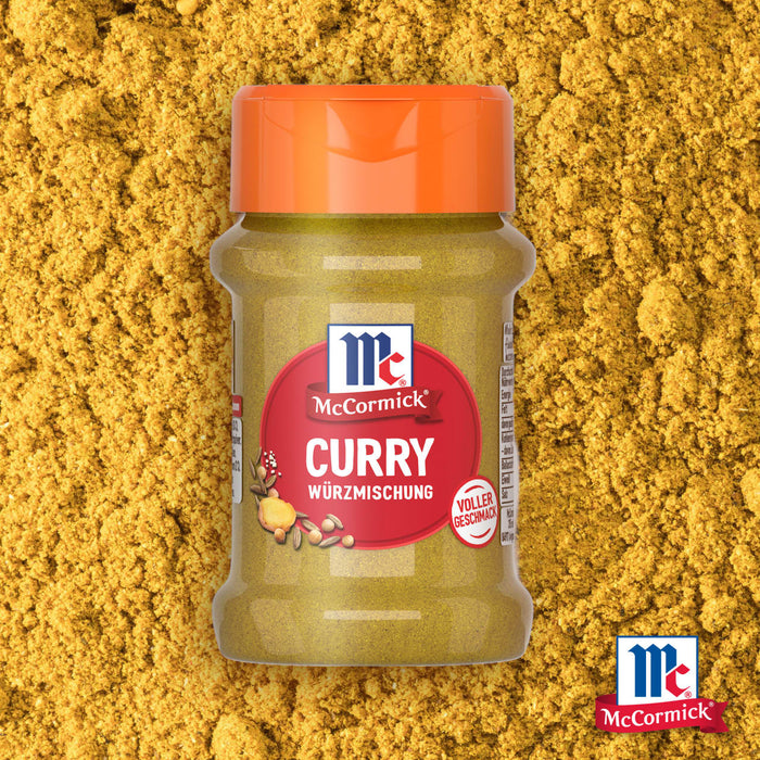 Eine Flasche McCormick Srpet Curry X06-Ge Gewürzmischung steht zentriert vor einem Hintergrund aus losem gelbem Currypulver.