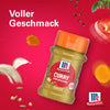 Eine Flasche Srpet Curry X06-Ge von McCormick wird vor einem leuchtend roten Hintergrund präsentiert umgeben von schwebenden Zutaten wie Kurkumascheiben und Pfefferkörnern um den vollen Geschmack zu betonen.