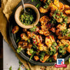 Knusprig zerdrückte Kartoffeln werden mit Srpet Garlic Granul X06-Ge gewürzt und mit einer lebendigen Kräuter-Chimichurri-Sauce auf einer dunklen Platte mit dem McCormick-Logo serviert.