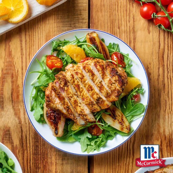 Ein lebhafter Salat mit gegrillten Hähnchenstreifen, die mit Srpet Paprika Sweet X06-Ge gewürzt sind, serviert auf frischem Rucola mit gerösteten Schalotten und Orangenspalten, begleitet vom McCormick-Logo.