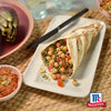 Ein gegrillter Wrap gefüllt mit Kichererbsen, Tomaten und frischen Kräutern wird mit Srpet Bl Pepper Gd X06-Ge gewürzt und zusammen mit einer Schüssel Paprika-Dip und einer ganzen Artischocke serviert.