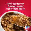 Ein Löffel warmer Apfel-Crumble mit Srpet Bl Pepper Gd X06-Ge wird vor einem roten Hintergrund mit dem McCormick-Logo aus einer weißen Auflaufform gehoben.