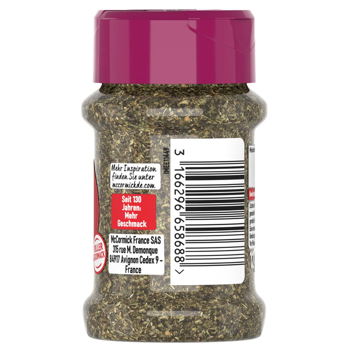 Die Rückseite eines durchsichtigen McCormick-Gewürzglases mit magentafarbenem Deckel, die die Unternehmensinformationen und den Barcode vor einem Hintergrund aus getrockneten grünen Kräutern zeigt.