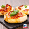 Drei Mini-Pizzen mit geschmolzenem Käse Peperoni und frischen Basilikumblättern werden auf einer Schieferplatte präsentiert um den Geschmack von Srpet Pizza Seas X06-Ge von McCormick zu unterstreichen.