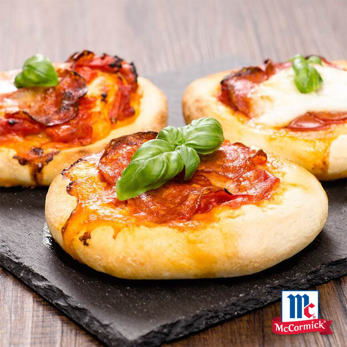Drei Mini-Pizzen mit geschmolzenem Käse Peperoni und frischen Basilikumblättern werden auf einer Schieferplatte präsentiert um den Geschmack von Srpet Pizza Seas X06-Ge von McCormick zu unterstreichen.