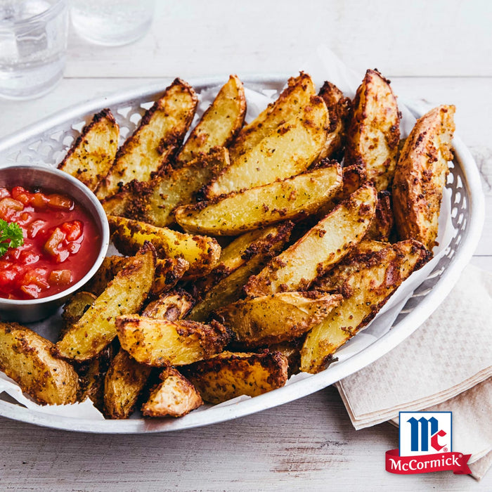 Ein silberner Korb gefüllt mit knusprigen Kartoffelspalten die mit Srpet Potatoe Seas X06-Ge gewürzt sind serviert mit einer kleinen Schüssel stückiger Tomatensalsa und dem McCormick Logo.